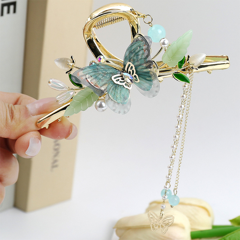 Butterfly tassel hair claw clip held in hand showing size