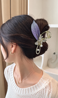 Purple embroidered leaf hair claw with gold-tone hardware worn in an updo. AI-assisted styling edit of a supplier photograph.