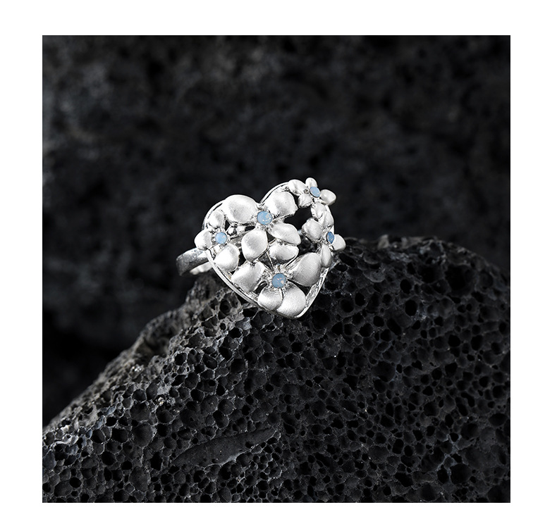 Silver-tone heart-shaped ring with sculpted flowers and pale blue glass accents