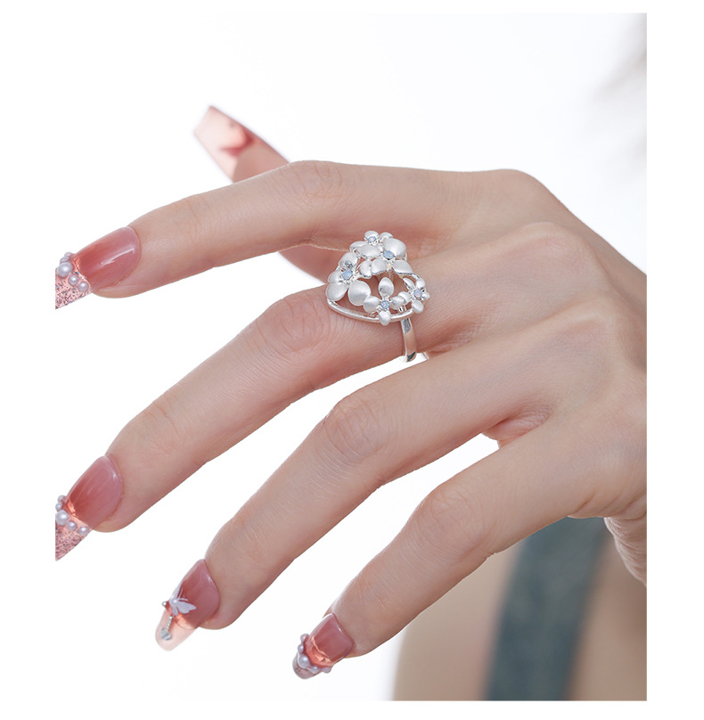 Side view of the silver-tone floral heart ring worn on a finger