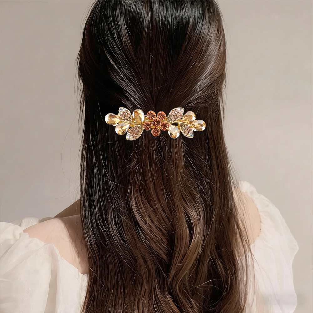 Supplier styling example of the Champagne floral leaf barrette in a half-up hairstyle