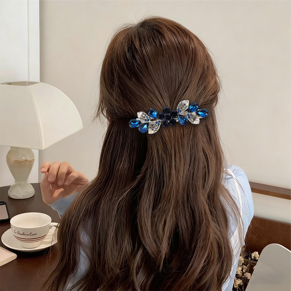 Supplier styling example of the Navy Blue floral leaf barrette in a half-up hairstyle
