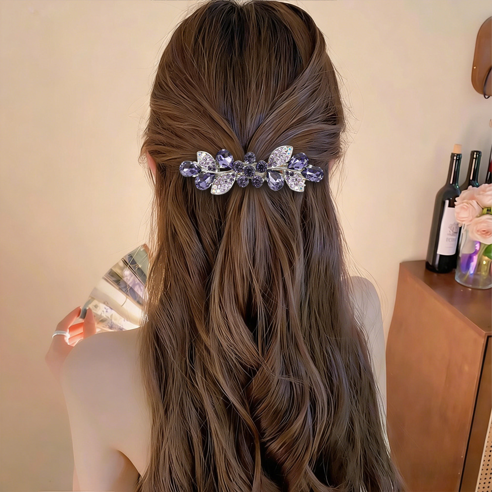 Supplier styling example of the Violet floral leaf barrette in a half-up hairstyle