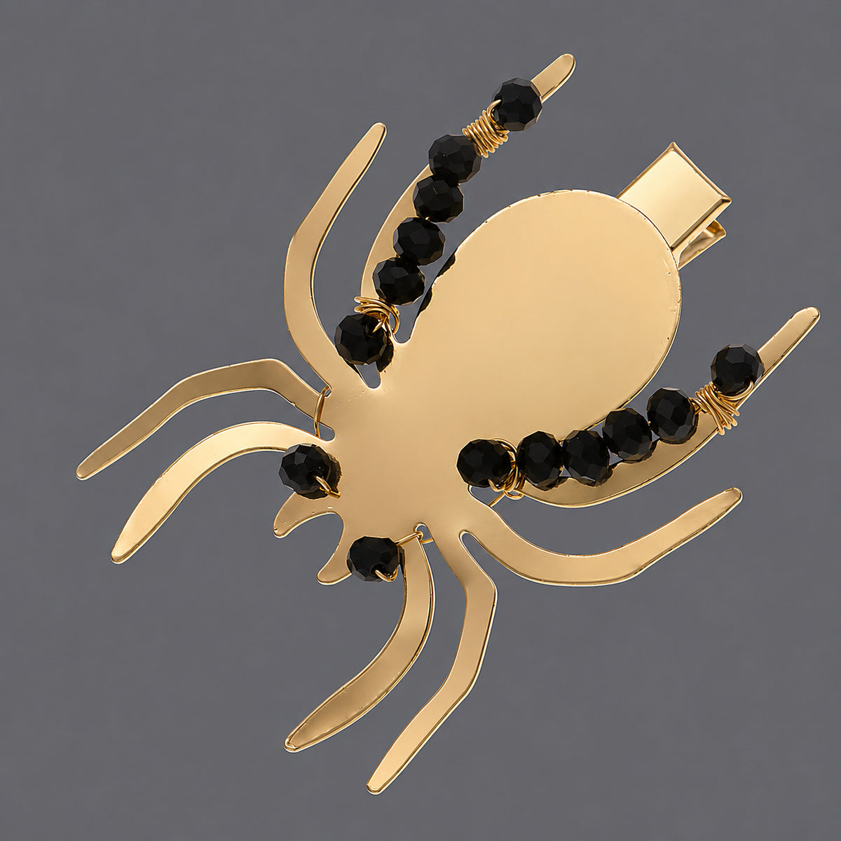 Gold-Tone Spider Hair Clip with Black Beads on a gray background