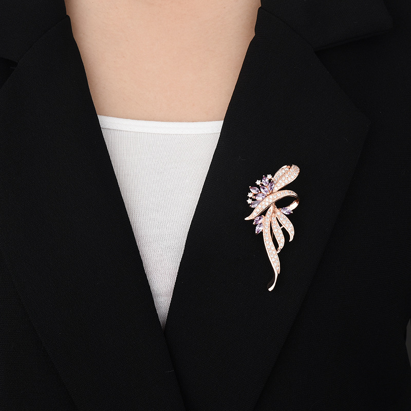 Rose-gold-tone ribbon brooch with purple cubic zirconia worn on a black blazer