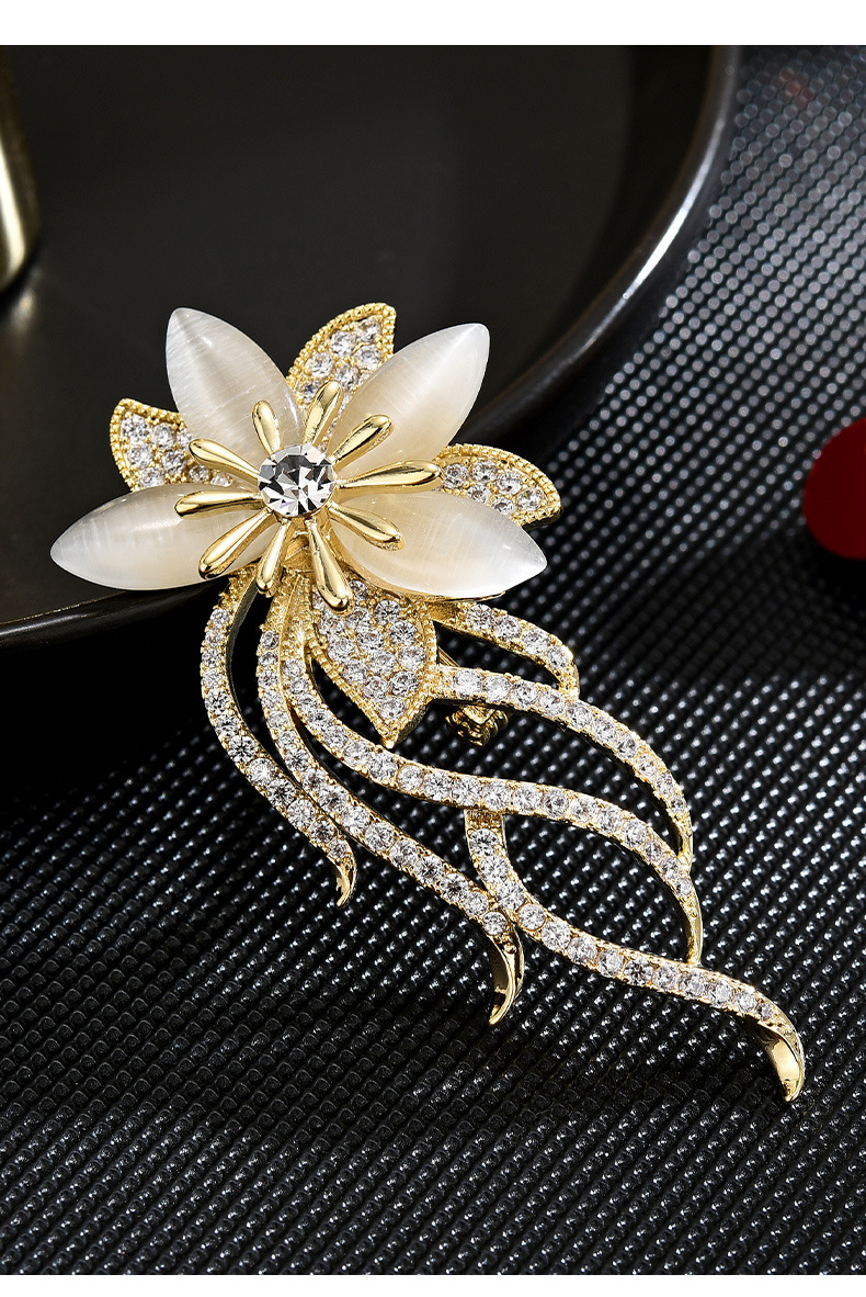 Gold-tone orchid brooch with imitation cat-eye petals and clear rhinestone trailing stems