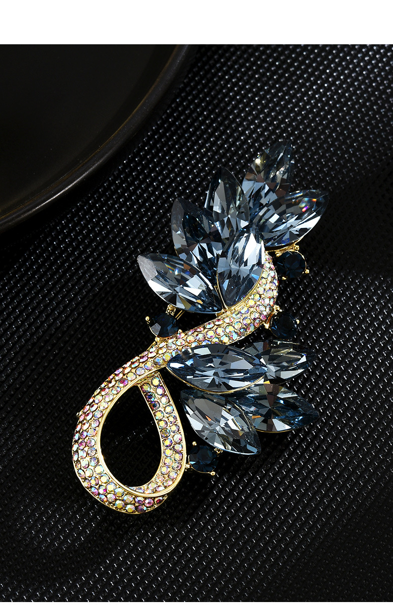 Gold-tone blue crystal leaf brooch with a rhinestone loop