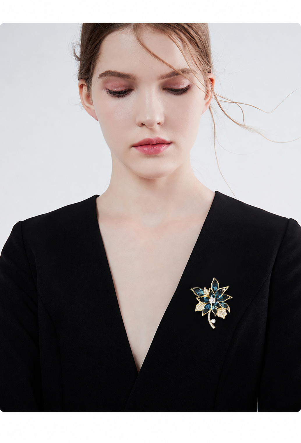 Gold-tone and blue petal flower brooch worn on the lapel of a black blazer