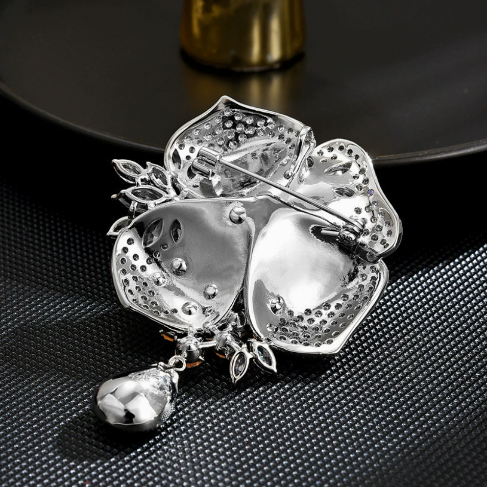 Back of the silver-tone rose brooch showing its pin fastening, openwork setting and hanging teardrop