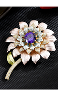 Pastel enamel flower brooch with a faceted purple center stone and gold-tone stem on a black textured surface