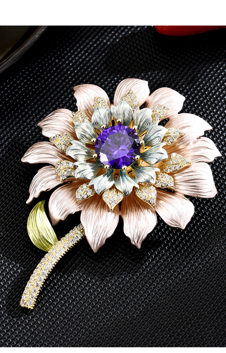 Pastel enamel flower brooch with a faceted purple center stone and gold-tone stem on a black textured surface