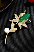 Gold-tone magnolia brooch with a green bud, clear decorative stones and a white freshwater pearl