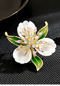 Gold-tone flower brooch with three pearlescent petals, green leaves, and pink and clear decorative stones
