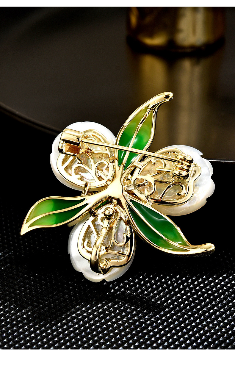 Back of the gold-tone flower brooch showing the pin fastening, clasp and green leaves