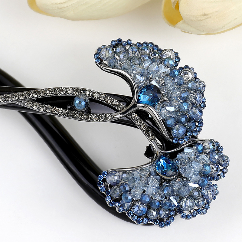 Close-up of the blue faceted stones and curved decorative stem on the ginkgo leaf hair clip