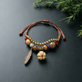 Hawthorn Seed charm bracelet with ceramic beads, brown adjustable cord and bronze-tone feather detail