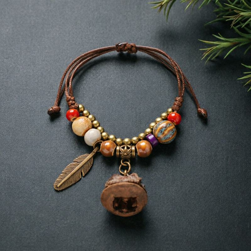 Eucalyptus Pod charm bracelet with ceramic beads, brown adjustable cord and bronze-tone feather detail