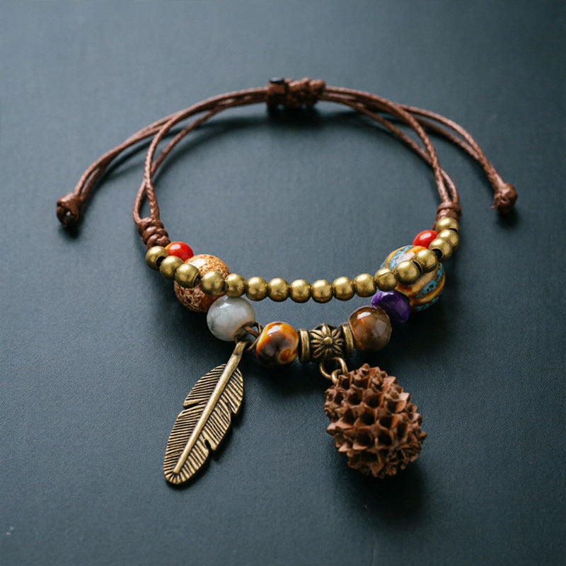 Spiky Seed Pod charm bracelet with ceramic beads, brown adjustable cord and bronze-tone feather detail