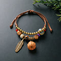 Mini Pumpkin charm bracelet with ceramic beads, brown adjustable cord and bronze-tone feather detail