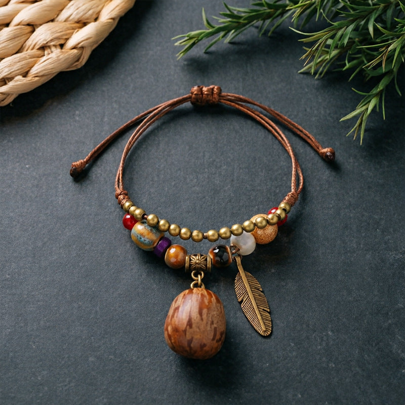 Patterned Seed charm bracelet with ceramic beads, brown adjustable cord and bronze-tone feather detail
