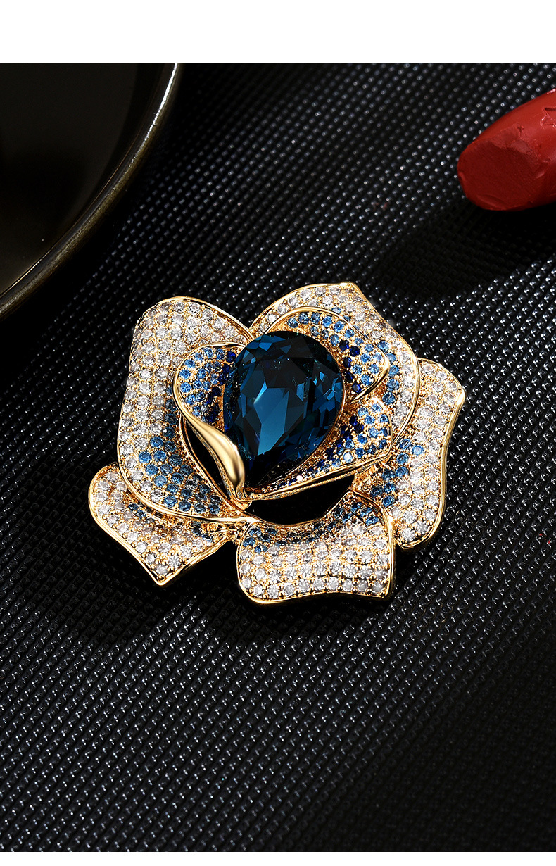 Gold-tone flower brooch with a faceted deep blue teardrop crystal and blue and clear decorative stones