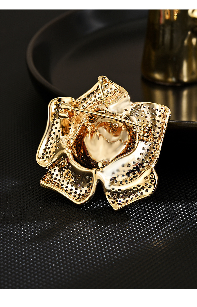 Back of the gold-tone flower brooch showing its pin fastening and clasp