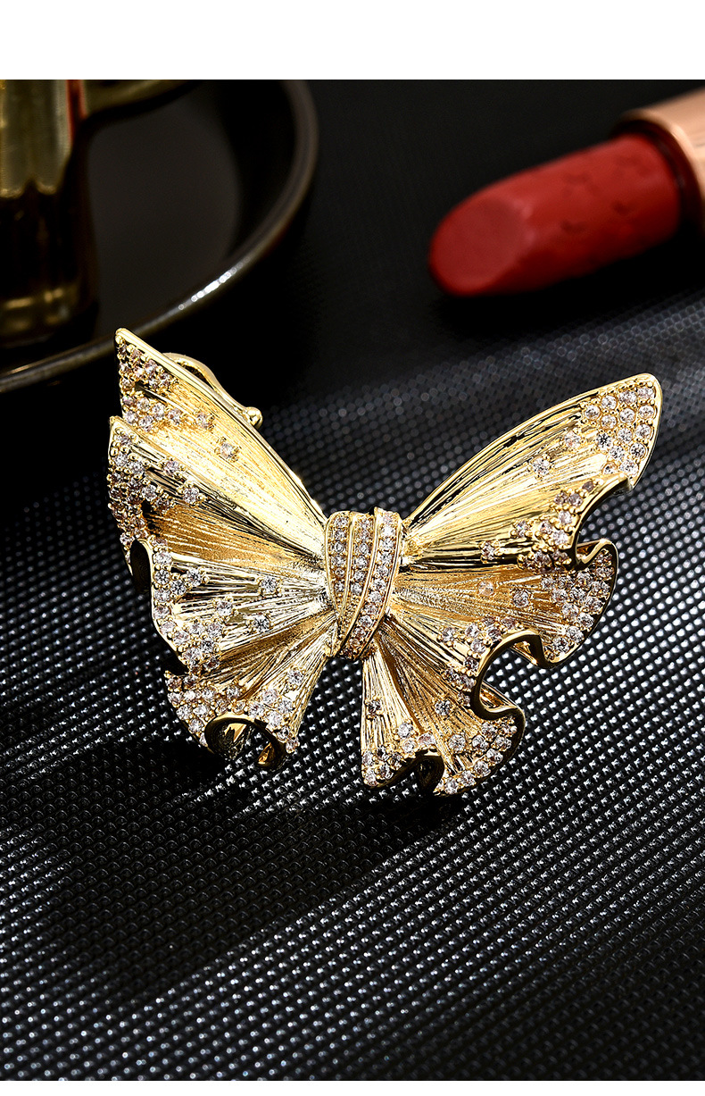 Gold-tone butterfly brooch with textured wings and clear cubic zirconia accents, front view