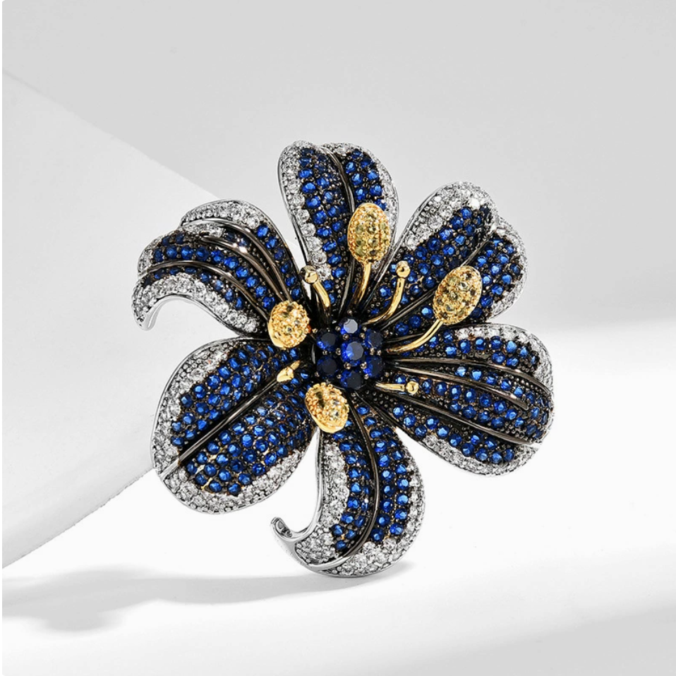 Sculpted blue lily cubic zirconia brooch with silver-tone edges and gold-tone stamens on a light background