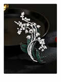 Silver-tone botanical brooch with green stone leaves, clear floral clusters and curved stems