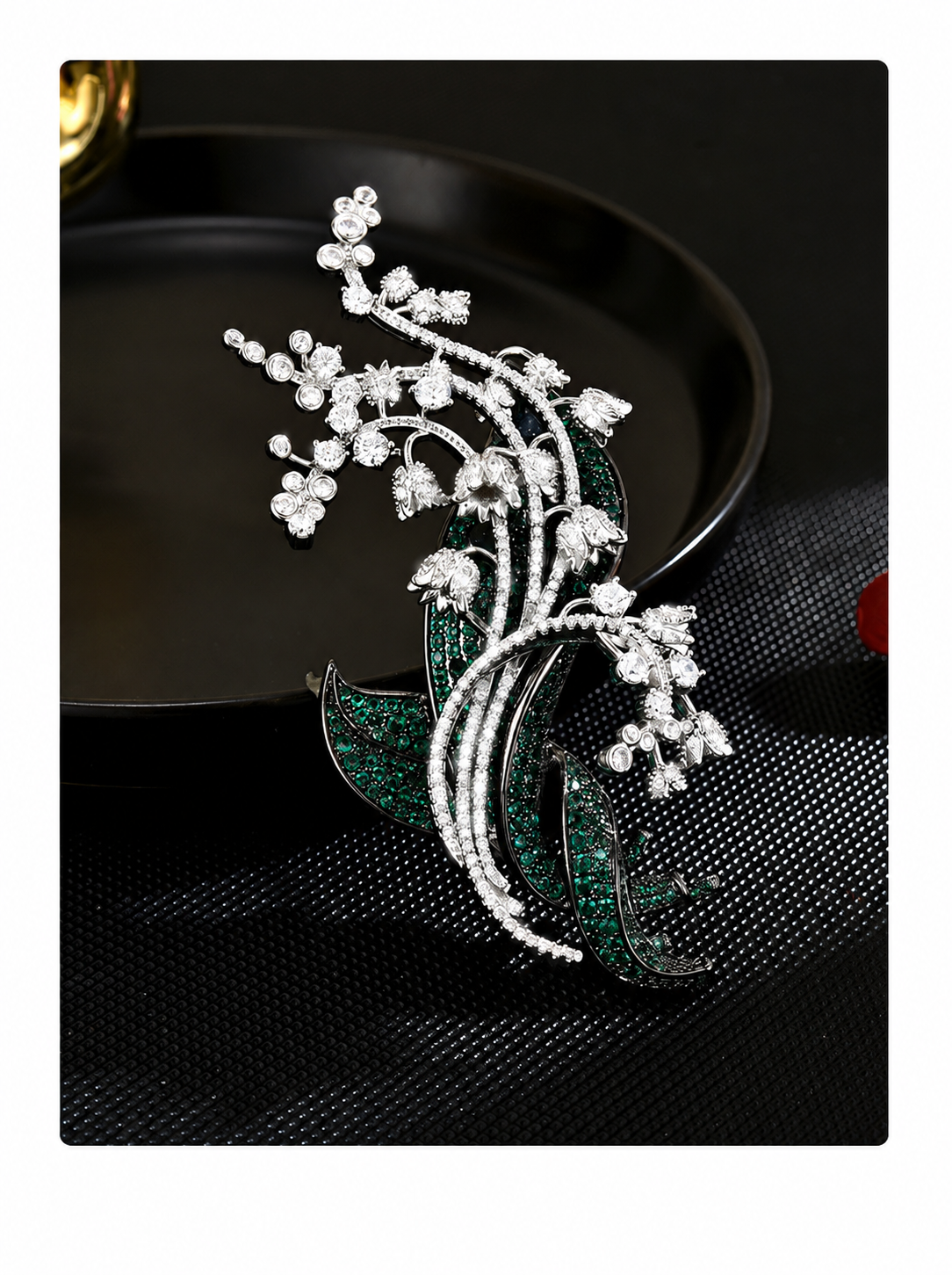 Silver-tone botanical brooch with green stone leaves, clear floral clusters and curved stems