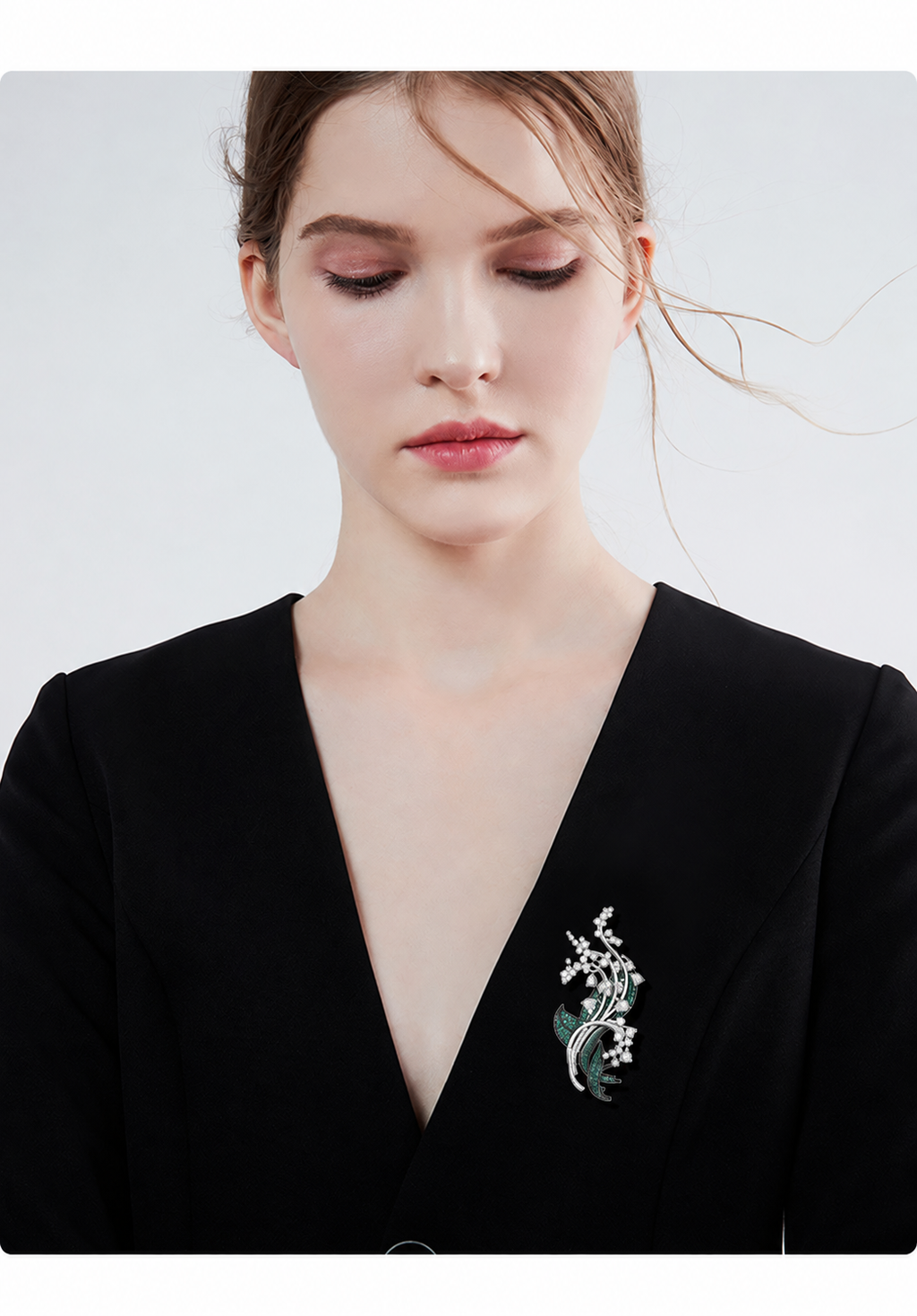 Silver-tone and green floral leaf brooch worn on the lapel of a black blazer