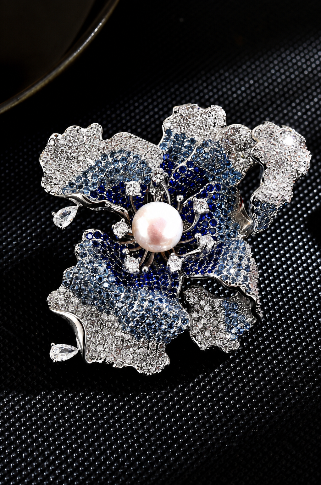 Silver-tone iris flower brooch with blue and clear decorative stones and a white freshwater pearl