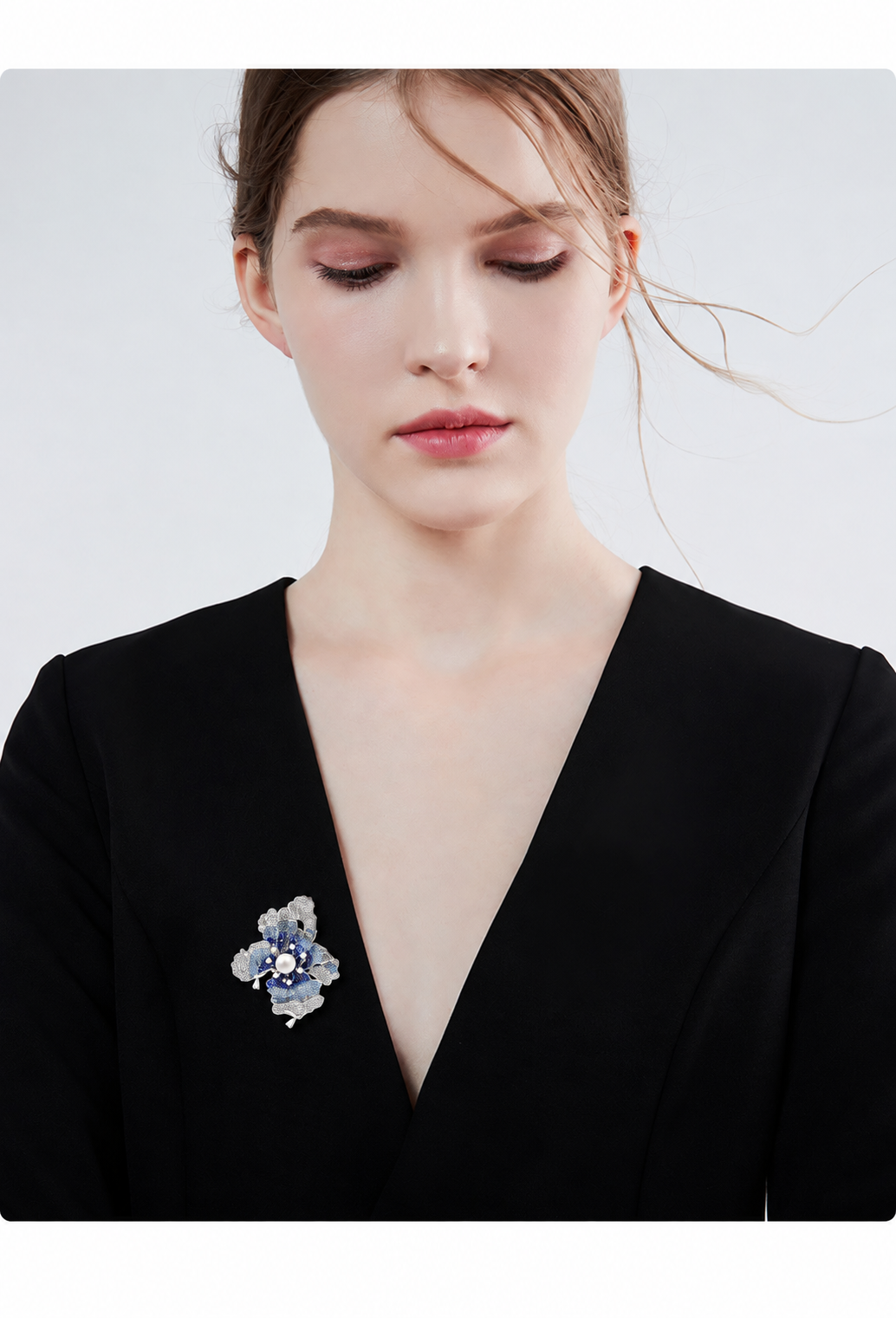 Blue and silver-tone iris brooch with a white freshwater pearl styled on a black garment