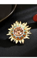 Gold-tone magnetic sunflower brooch with a champagne-colored center and blue and clear accents