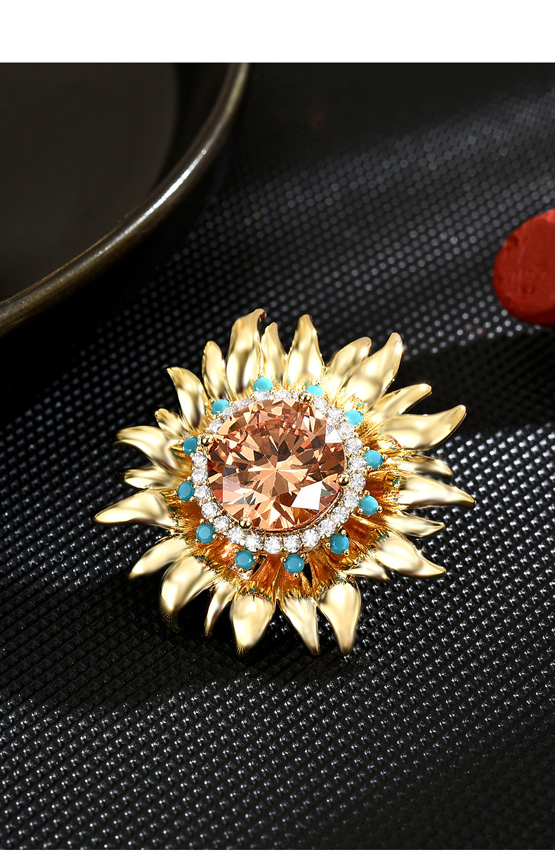 Gold-tone magnetic sunflower brooch with a champagne-colored center and blue and clear accents