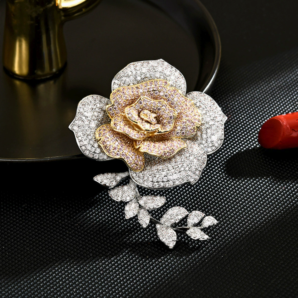 Two-tone rose brooch with pale pink cubic zirconia on gold-tone inner petals, clear stones on silver-tone outer petals and a leafy stem