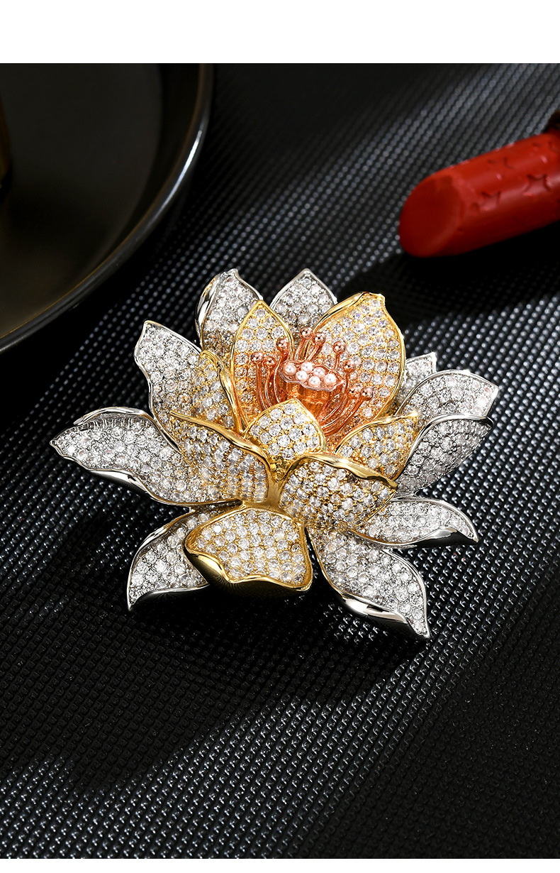 Tri-tone lotus brooch with clear cubic zirconia and shell-bead accents on a black textured surface