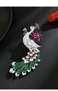 Silver-tone peacock brooch with a pink flower, sparkling clear body and long green feather tail