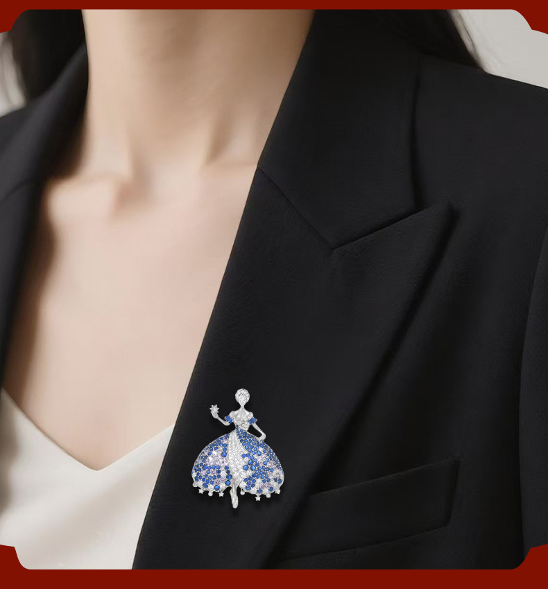 Blue and silver-tone ballerina brooch worn on the lapel of a black blazer