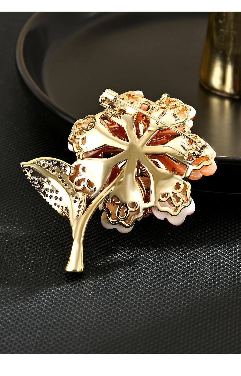 Back of the orange flower brooch showing its gold-tone openwork setting, stem and brooch pin