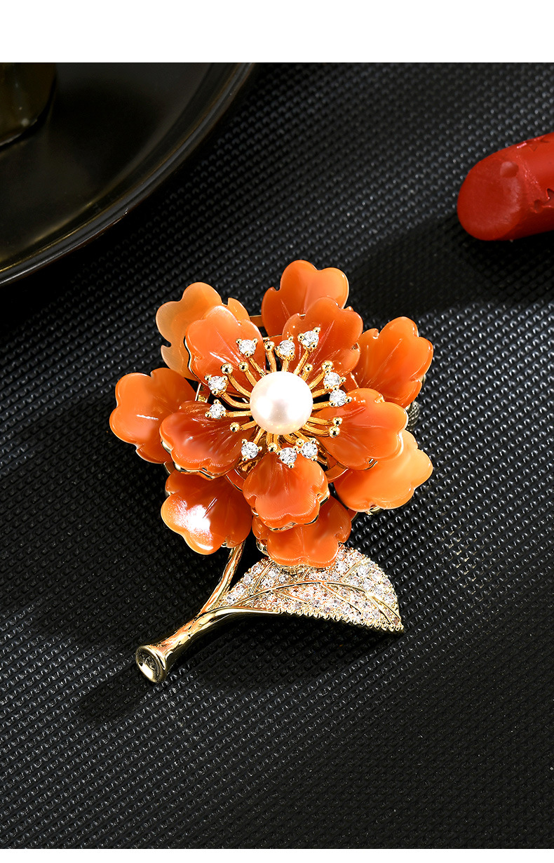 Orange mother-of-pearl flower brooch with a freshwater pearl center, gold-tone stem and sparkling leaf
