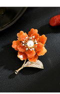Orange mother-of-pearl flower brooch with a freshwater pearl center, gold-tone stem and sparkling leaf