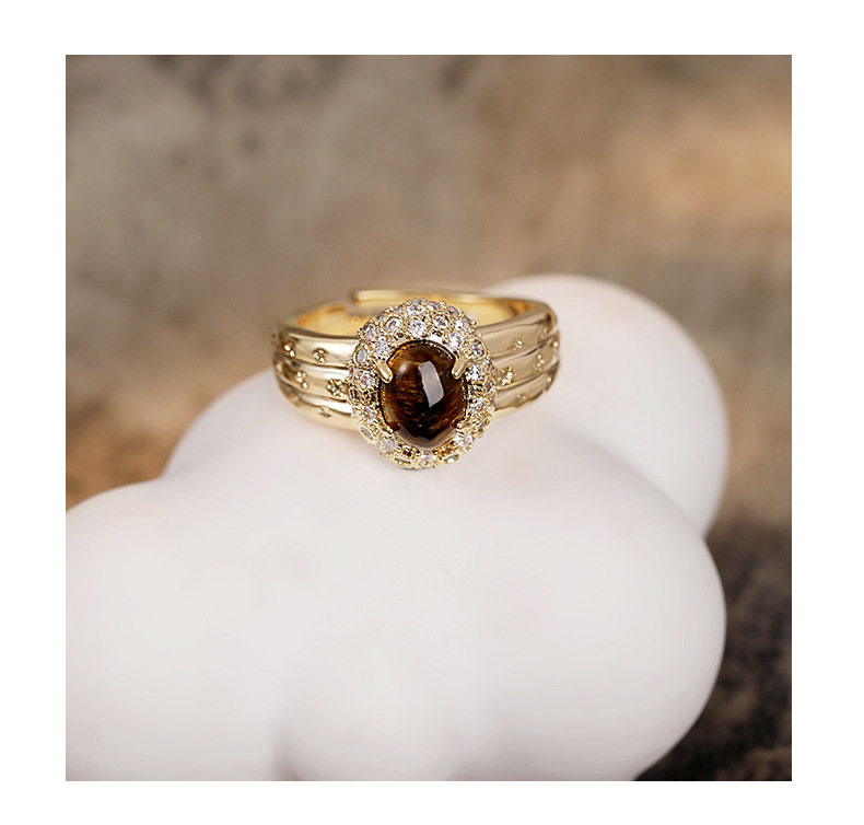 Front view of a gold-tone oval brown tiger's eye halo ring with a three-row band