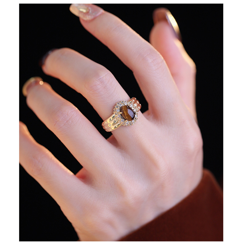 Gold-tone oval brown tiger's eye halo ring worn on a hand