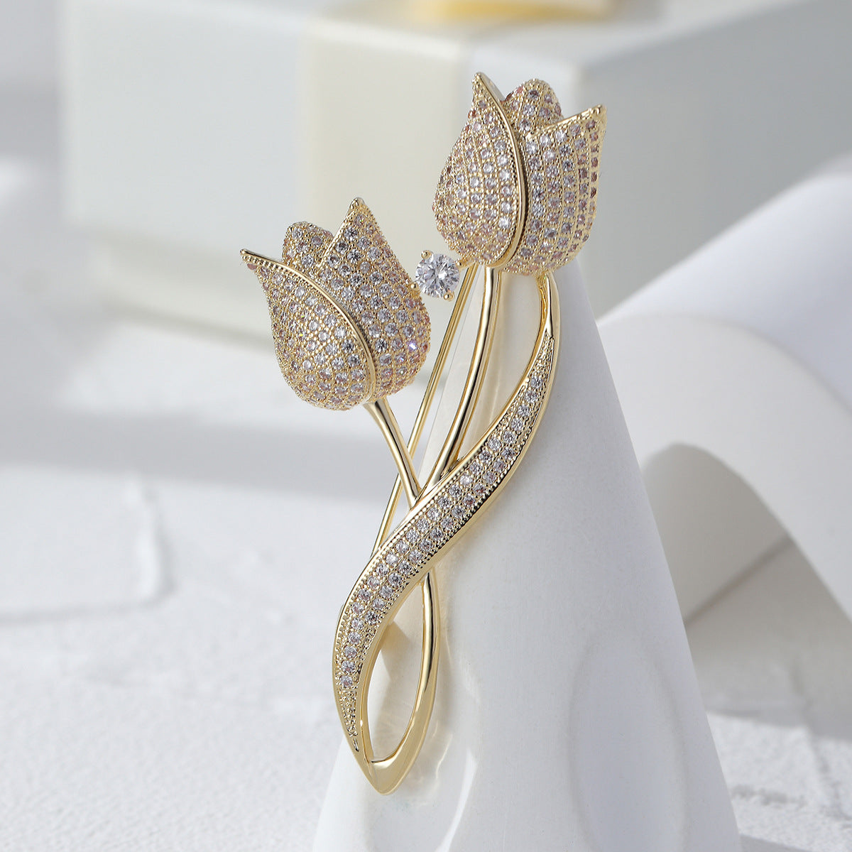 Gold-tone twin tulip brooch with sparkling clear stones, slender stems and a curved leaf on a light background